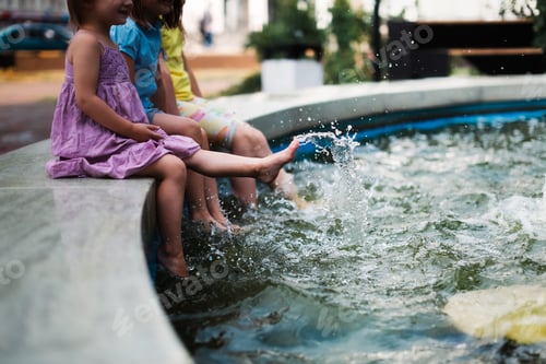 Preview: Happy European children play with water in the city fountain, child safety and freedom in the city.