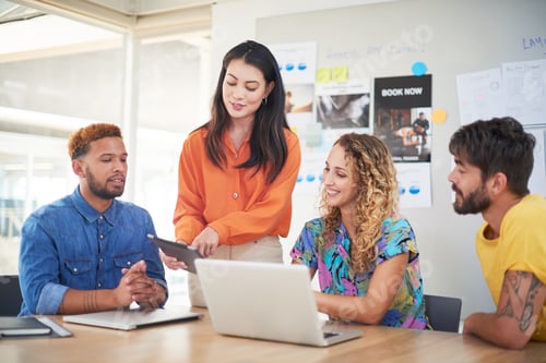 Preview: Shot of a group of young businesspeople using a laptop and digital tablet in a modern office