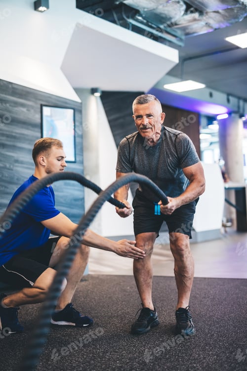 Preview: Senior man exercising with ropes at the gym.