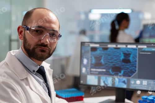 Preview: Medical researcher in biotechnology laboratory looking at camera