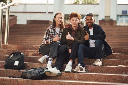 Preview: Looking at the camera. Young students in casual clothes are together outdoors