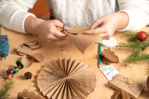 Preview: girl makes Christmas tree decorations out of paper with her own hands. step 2