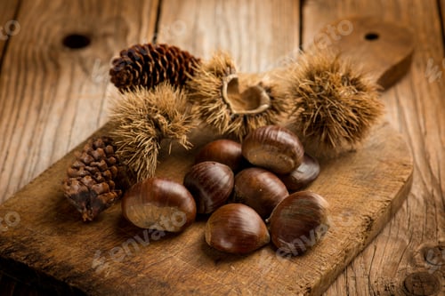 Preview: raw chestnuts with hedgehog over wooden table