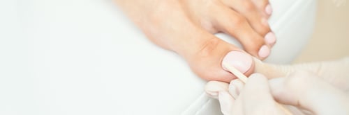 Preview: Close-up of manicure treatment on female foot with nail polish application