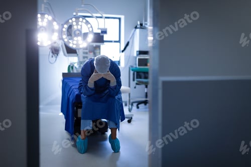 Preview: Upset female surgeon sitting on the operation bed in operation room