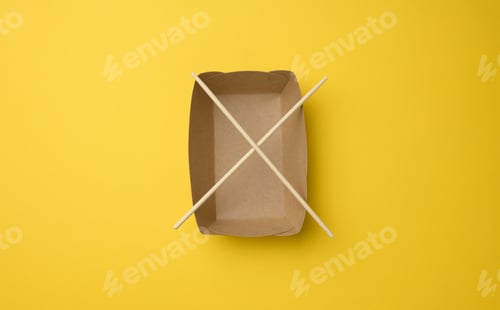 Preview: Empty brown paper plate and wooden chopsticks on a yellow background, top view