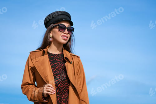 Preview: Female portrait of a young woman against a blue sky in sunglasses