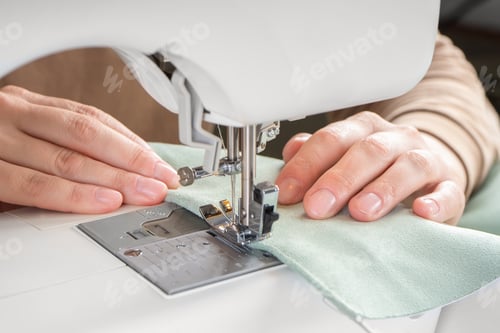 Preview: Female Hands Stitching Green Fabric On Modern Sewing Machine At Workplace In Atelier