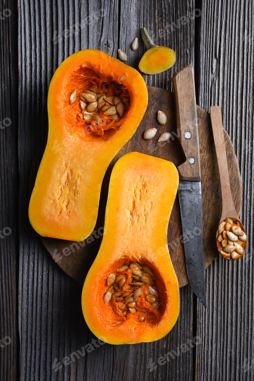 Preview: Two half of raw butternut squash with wooden spoon