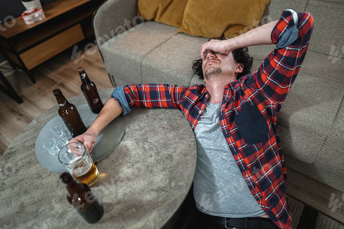 Preview: Drunk young man suffering from hangover at home