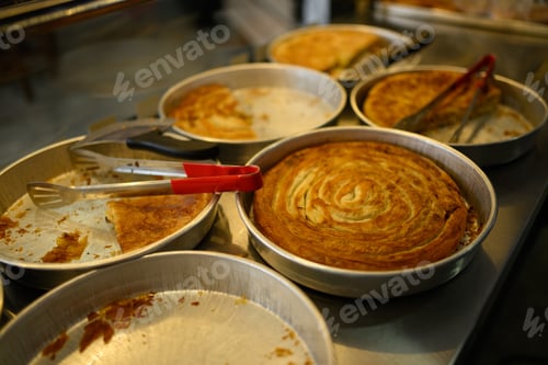 Preview: Freshly baked pies in aluminum pans with serving tongs on the table