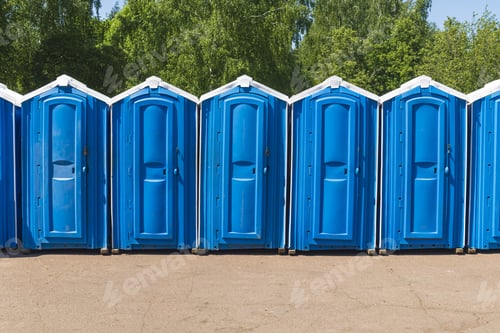 Preview: Blue plastic biodegradable toilet stalls line up in an outdoor activity area.