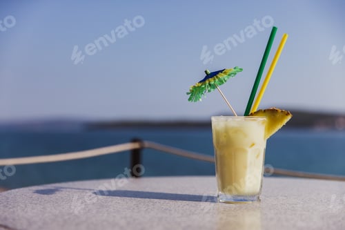 Preview: Cold glass of Pina Colada stand on table near the sea