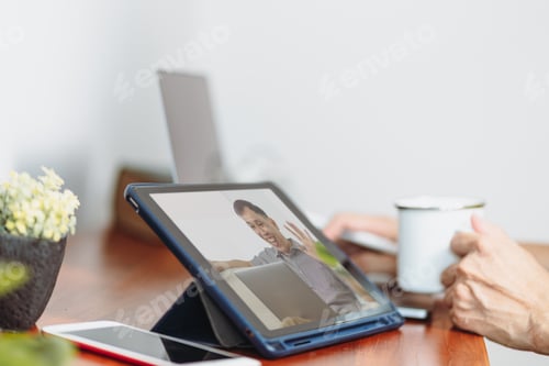 Preview: A tablet computer screen on the table displays a cheerful asian man