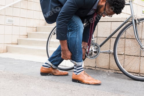 Preview: Young male cyclist rolling down jeans on railway station platform