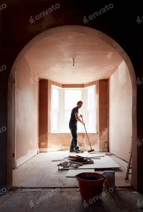 Preview: A builder sweeping and tidying up in a renovated replastered house with an archway.