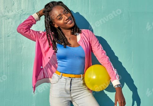 Preview: Young black woman with a yellow ball in front of a blue wall