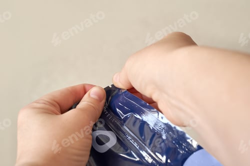 Preview: Close-up of hands opening a plastic snack bag with tear notch for easy access