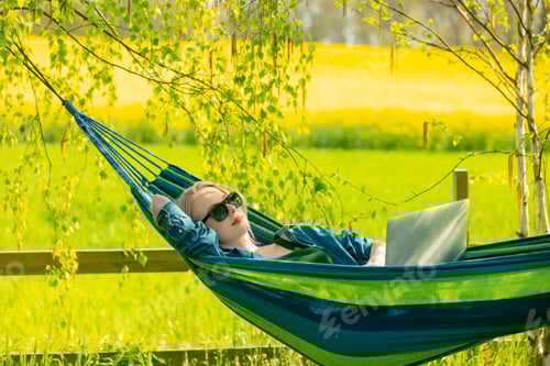 Preview: Woman Relaxing in Hammock with Laptop in Nature
