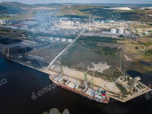 Preview: A majestic bulk carrier, laden with raw materials, awaits in the port. The aerial view is