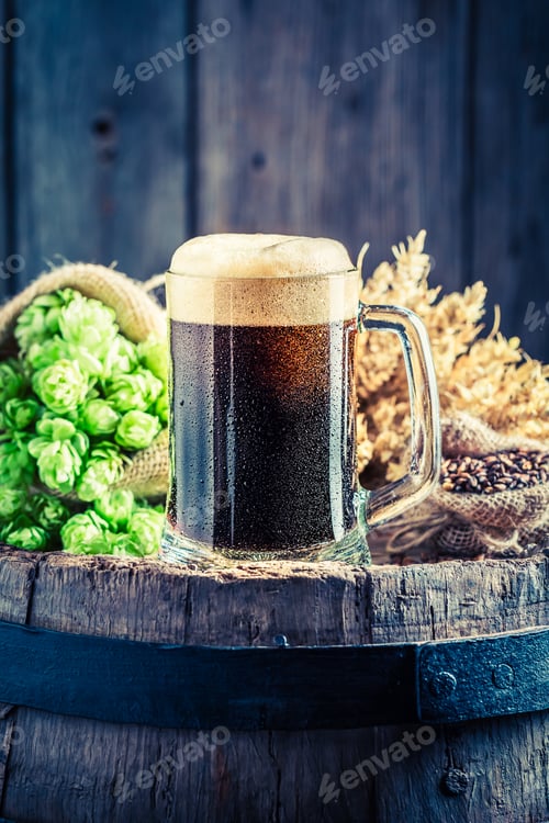 Preview: Pint of dark beer, wheat and hops on old barrel