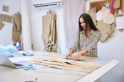 Preview: Smiling brunette at cutting table lays out pattern on fabric