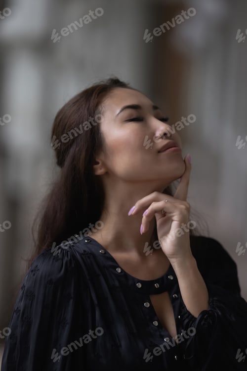 Preview: A beautiful Asian girl with black hair in a white dress against a yellow wall.