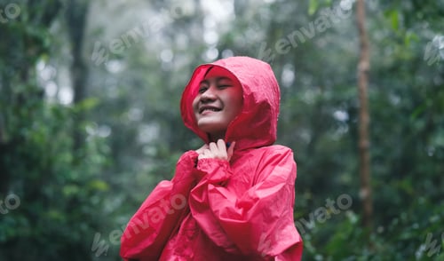 Preview: Smiling woman in red raincoat enjoying the forest