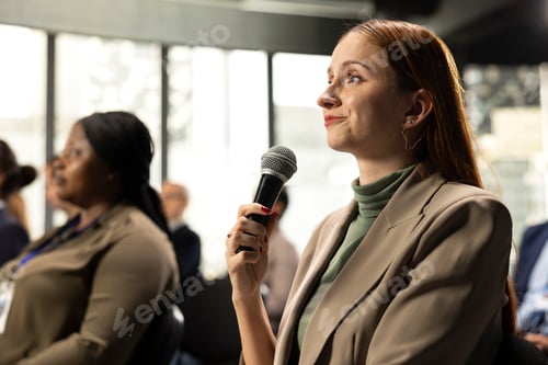 Preview: Young woman in attendance asking a question on microphone during conference