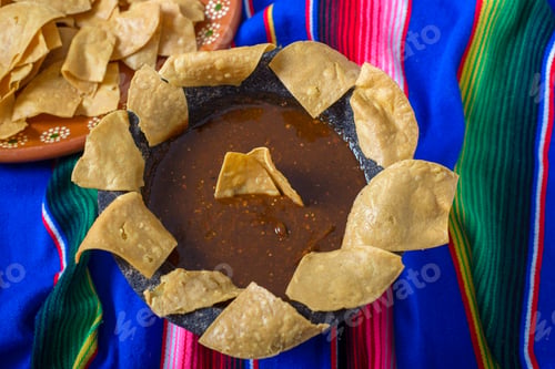 Preview: Totopos around a molcajete with red sauce on a colorful serape.
