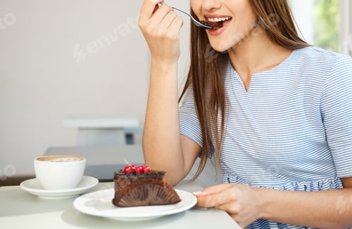 Preview: Young attractive Caucasian lady enjoy eating chocolate cake with hot coffee in modern coffee shop at