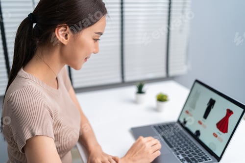 Preview: Asian young woman use laptop computer for shopping product sell online on website in smartphone.