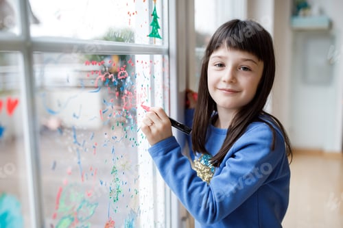 Preview: Cute little girl drawing merry christmas wishes on window