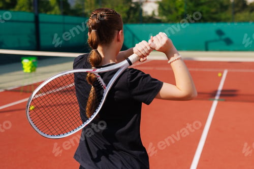 Preview: Girl tennis player winding up for a shot, view from behind.