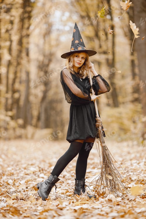 Preview: Young witch in forest on Halloween with a broom