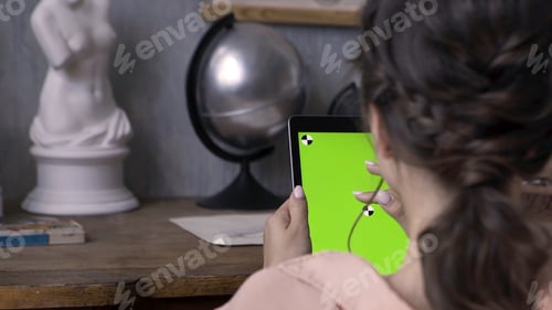 Preview: Woman hands holding tablet pc with green screen in the art studio with concrete wall and silver