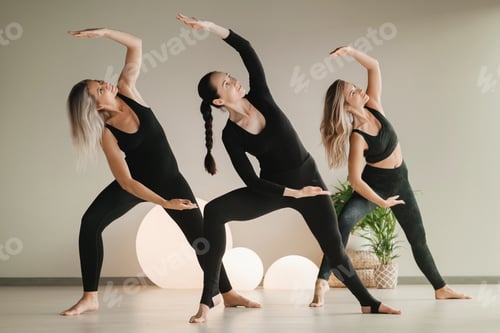 Preview: A group of girls in black doing yoga poses indoors. Women are engaged in fitness