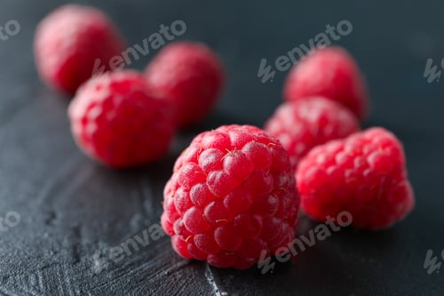 Preview: Raspberries on black cement background, closeup and space for text