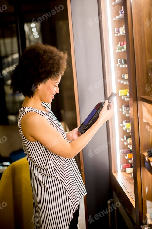 Preview: Young woman stands looking bottle of wine
