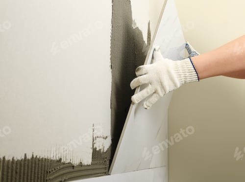Preview: Worker installing ceramic tile on wall, closeup. Space for text