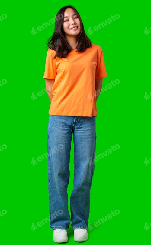Preview: Smiling person stands confidently in orange shirt and blue jeans against a green background