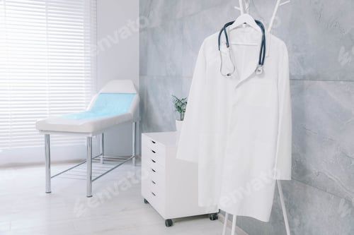 Preview: White doctor's gown and stethoscope on rack in clinic