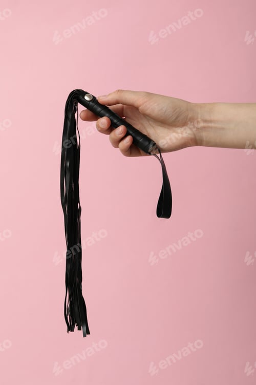 Preview: Flogger in hands on a pink background.