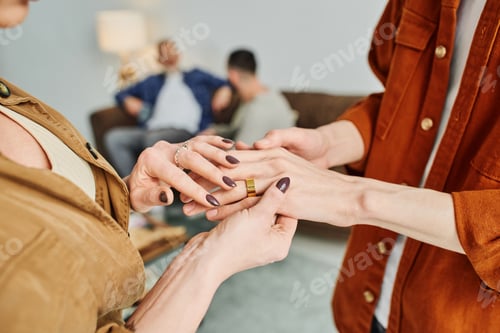 Preview: partial view of woman touching hands of gay man with wedding ring at home