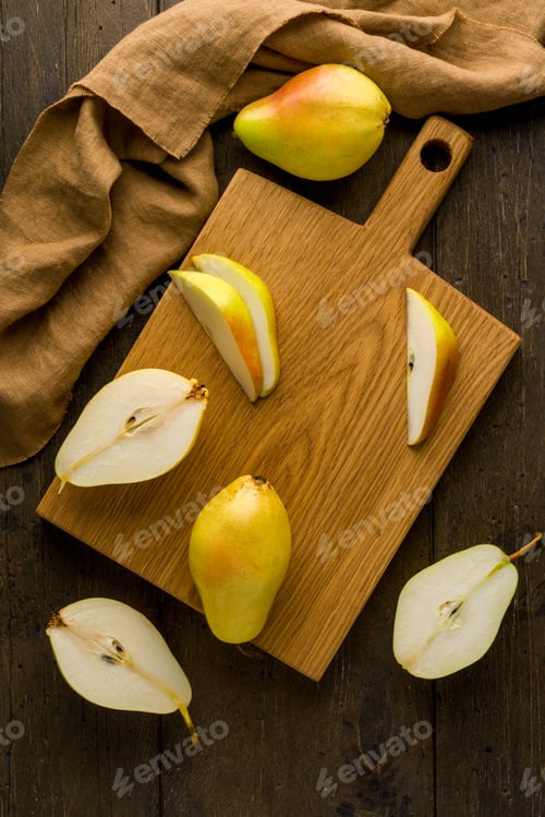 Preview: Sliced yellow pears on wooden cutting board. Food background vertical