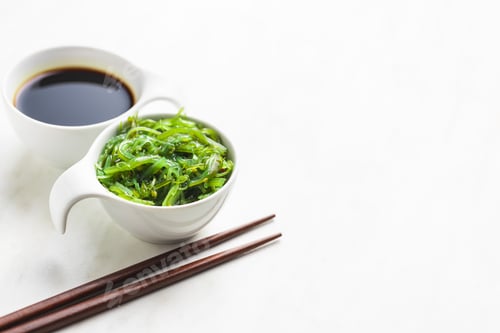 Preview: Green wakame. Seaweed salad and soy sauce in bowl.