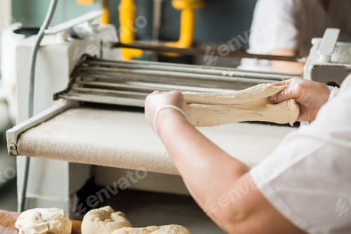 Preview: Woman baker working with dough at the bakery.