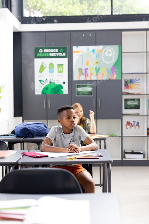 Visualização: Vertical de estudante afro-americano sentado na mesa ouvindo na sala de aula, espaço de cópia