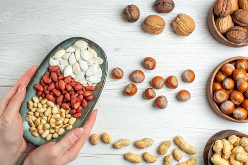 Preview: top view nut composition peanuts seeds hazelnuts and walnuts on white background nut pistachios