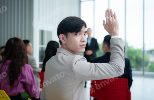 Preview: Portrait of a young Asian businessman sitting behind a seminar room with a colleague